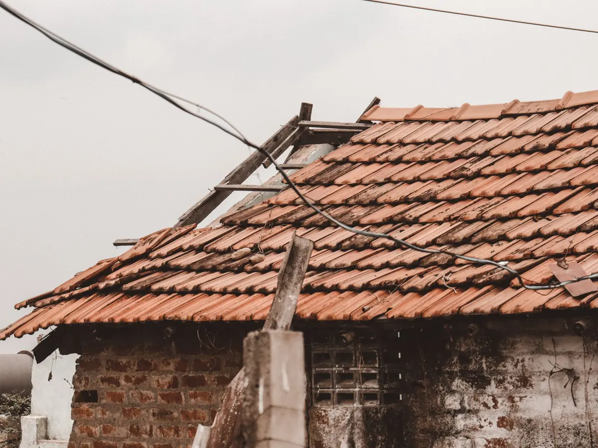An old rural house with a damaged clay tile roof in Chennai, India, showing signs of decay.