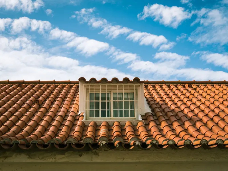 Close-up of a terracotta tiled roof with a skylight window in sunny Marbella, Spain.