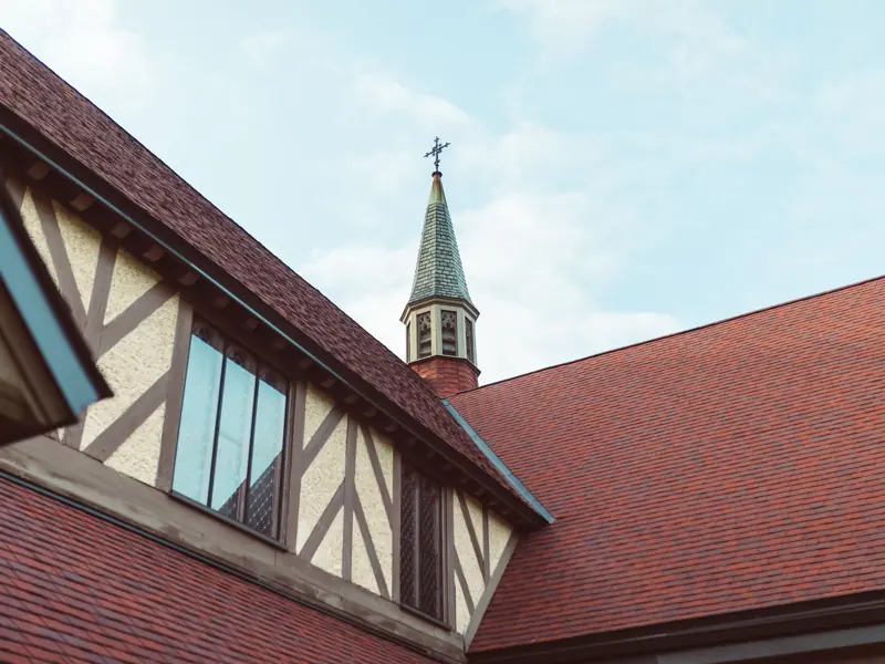 Close-up view of a church steeple with timbered architecture against a clear sky.