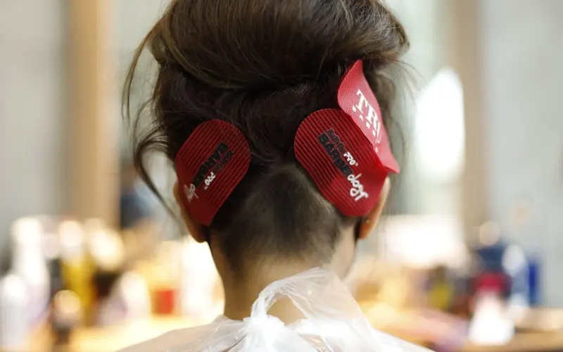 Back view of woman with brown hair and clips in salon setting.