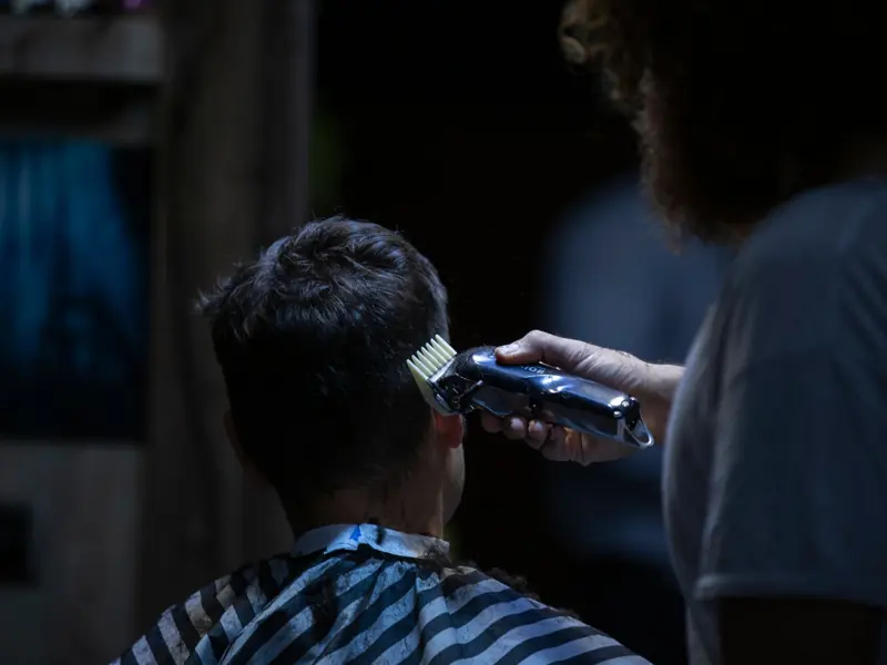 Barber using electric clipper for a precise haircut in a barber shop.