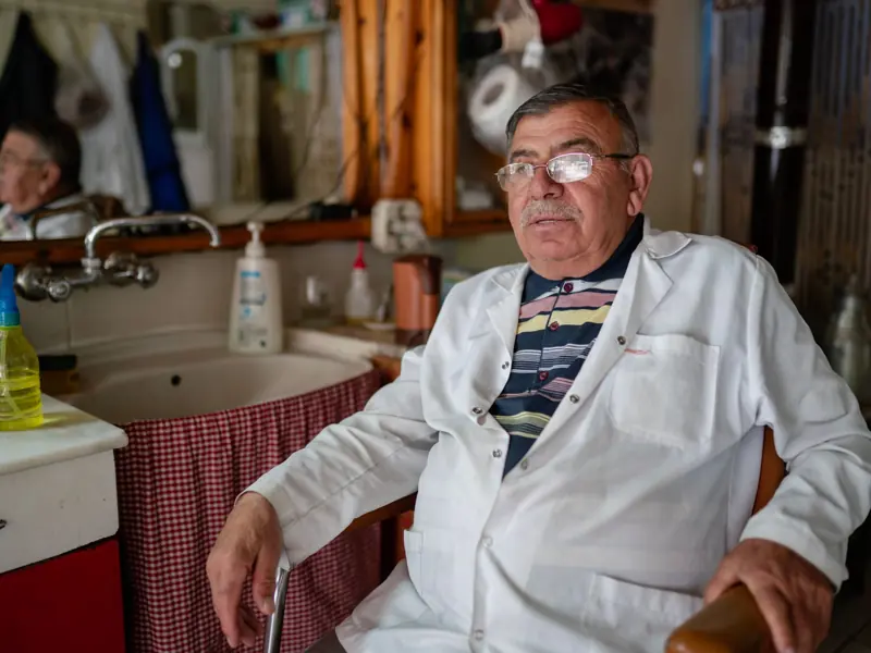 Elderly barber in Göreme, Türkiye, relaxing in his traditional shop, reflecting local culture.