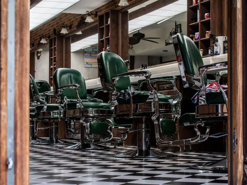 Charming vintage barber shop with classic green chairs and checkered floor tiles.
