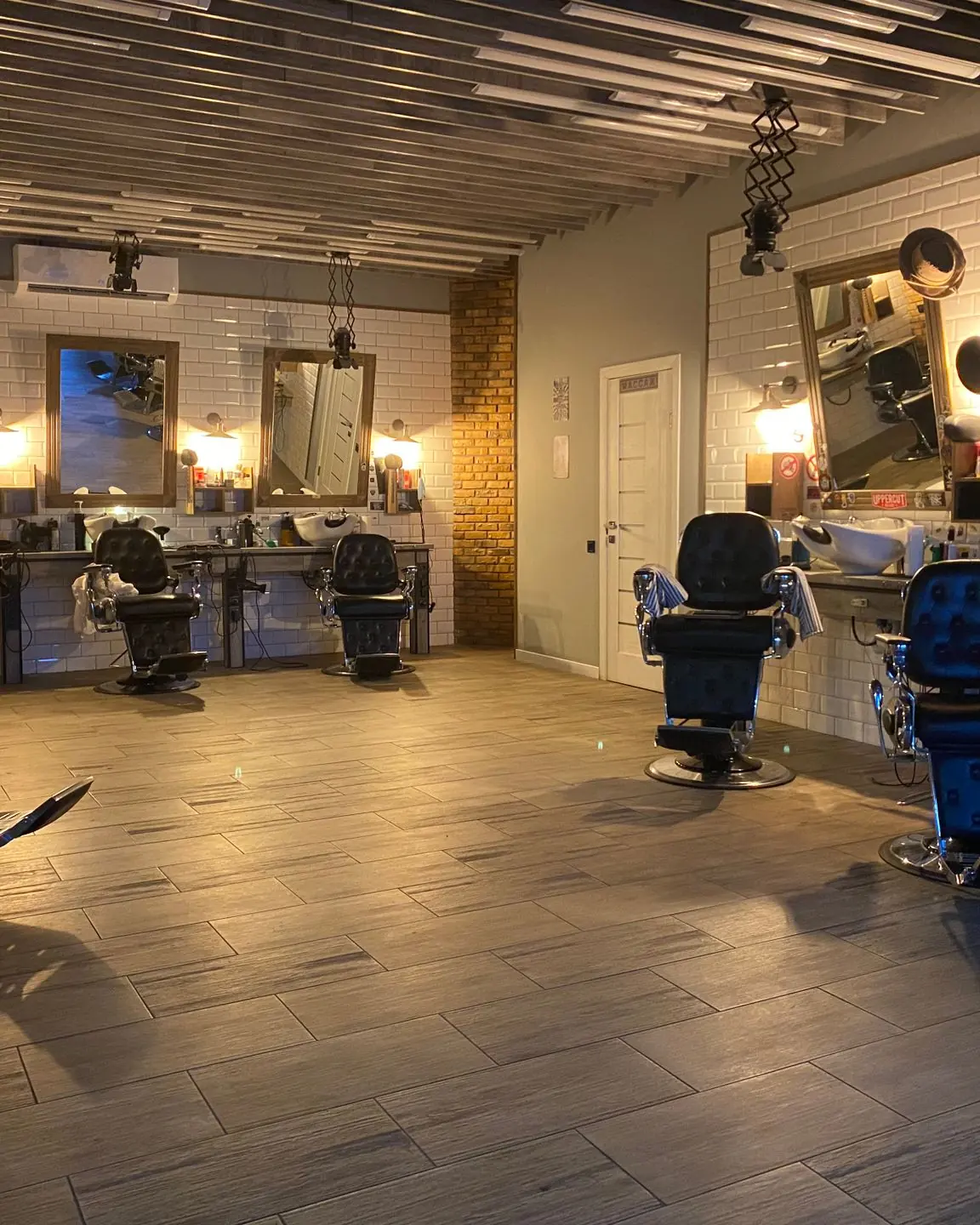 Spacious and stylish hair salon featuring empty barber chairs, mirrors, and elegant lighting.