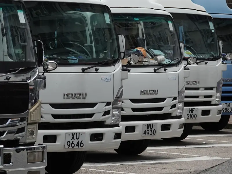 Parked Isuzu trucks lined up in the city, ready for delivery. Ideal for transport and logistics themes.
