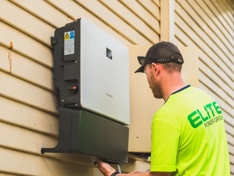 A skilled technician working on the installation of a solar inverter system outdoors. Energy efficiency solution.