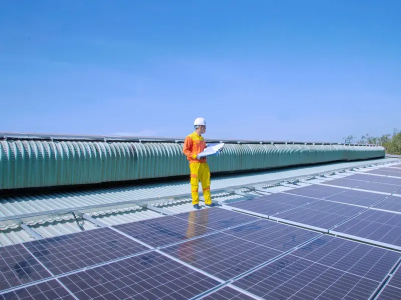 Technician examining solar panels on a rooftop, emphasizing renewable energy.