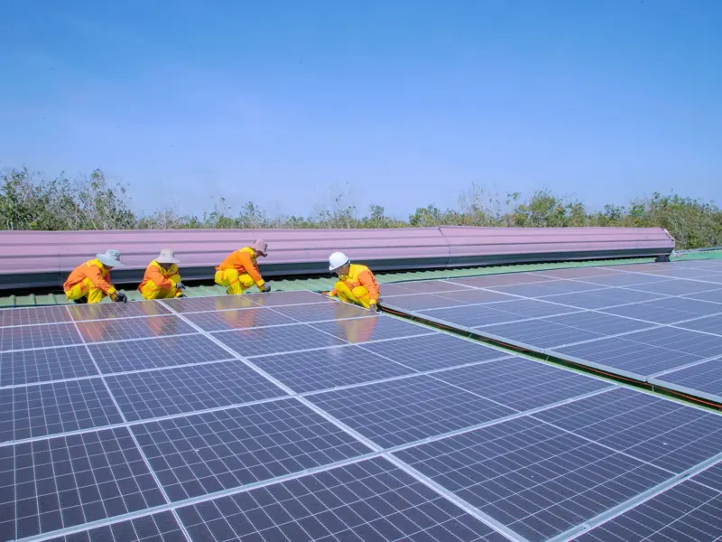 Workers installing solar panels on a sunny day, promoting renewable energy and sustainability.