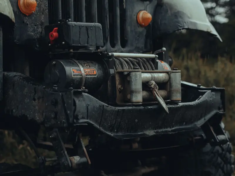 Detailed view of an off-road vehicle bumper with a metal tow winch, ready for adventure.