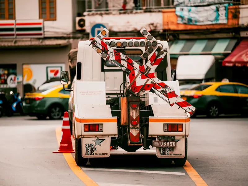 Utility vehicle with traffic barriers on a busy street in Bangkok, Thailand.