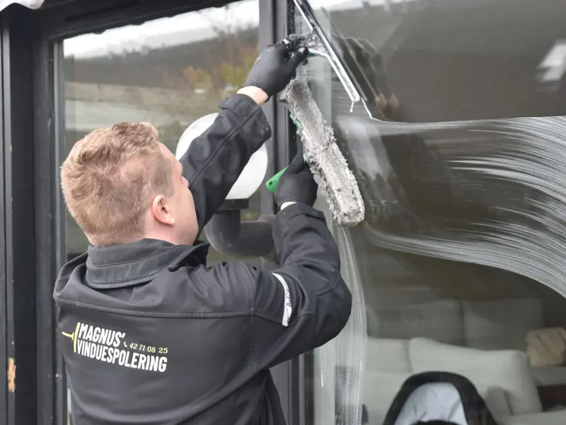 Professional cleaning service washing a large glass window. Clean and efficient work by a dedicated individual.
