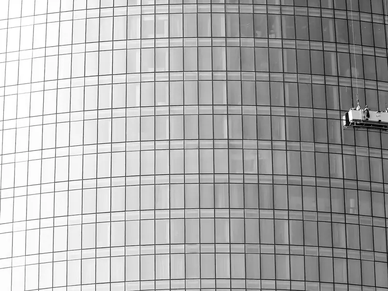 Dramatic shot of window cleaners scaling a glass skyscraper facade.